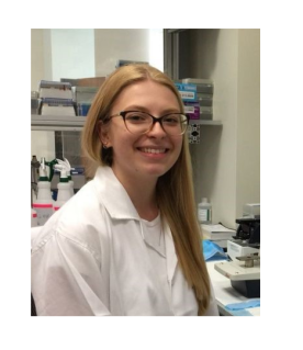 Merima Šabanović is posing in a lab coat. She is smiling, have long blond hair and glasses