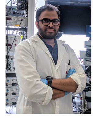 Dr. Suraj Honnuraiah is wearing a labcoat and is posing in from of his electrophysiology settup